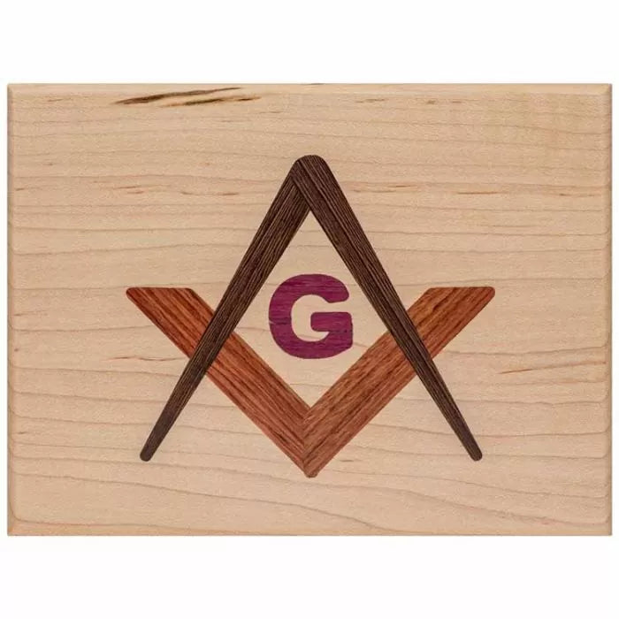 Wooden plaque with inlaid square, compass, and G symbol for woodworking decor.