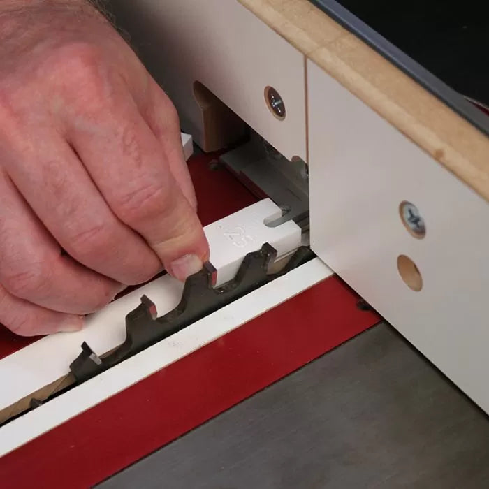 Hand using dado blade setup jig on table saw for woodworking precision