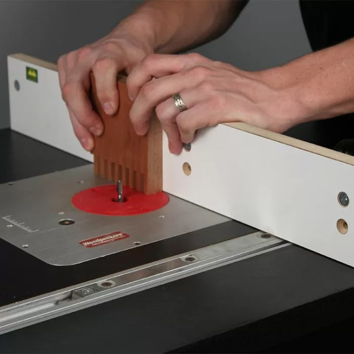 Person using woodworking router table and fence to cut dovetail joints in wood