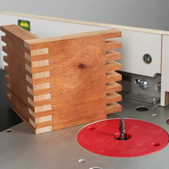 Router table with a box joint jig and finger-jointed wooden box for woodworking.