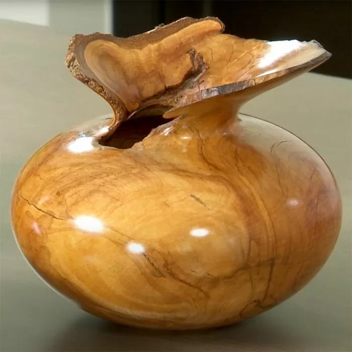 Polished natural edge wooden bowl with unique grain on a smooth tabletop, woodworking project