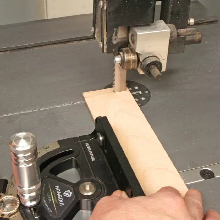 Cutting wood with a bandsaw and miter gauge on a workshop table