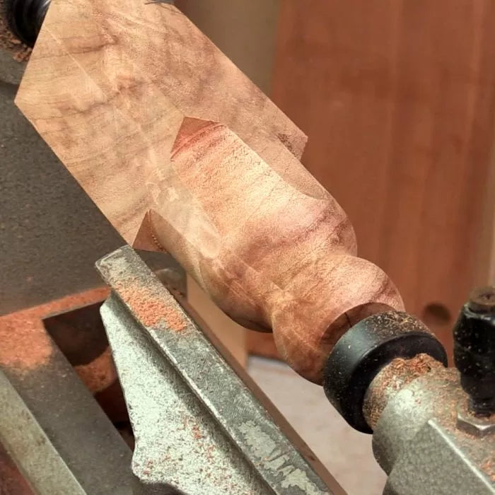 Wood lathe turning a decorative wood spindle with cove and bead transition details.