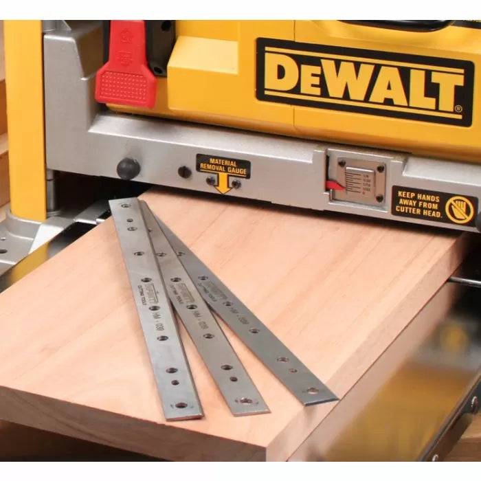 Planer knives on a wooden board in front of a DeWalt thickness planer for woodworking.