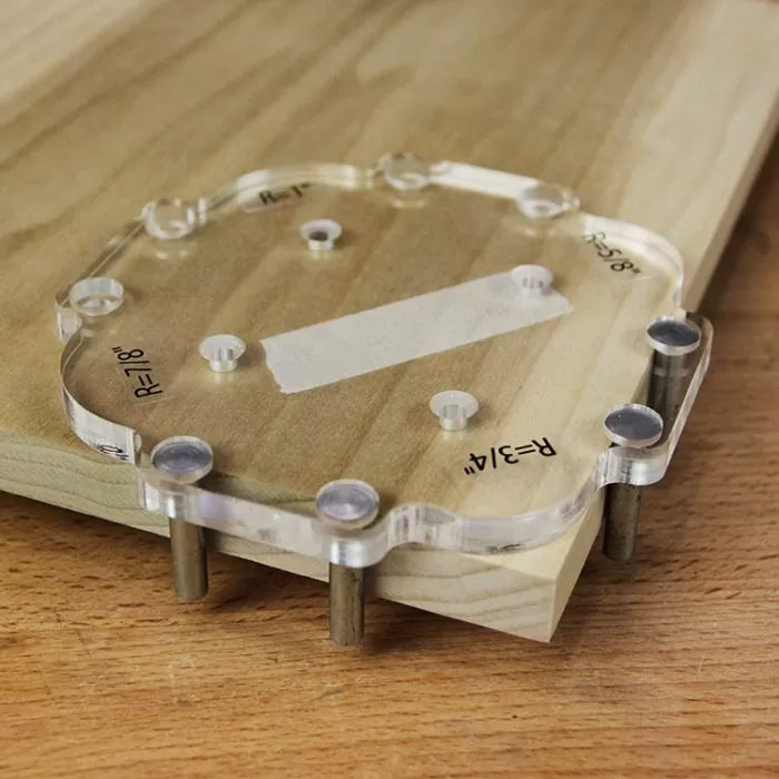 Acrylic woodworking jig template clamped to wood board for precise router edge work
