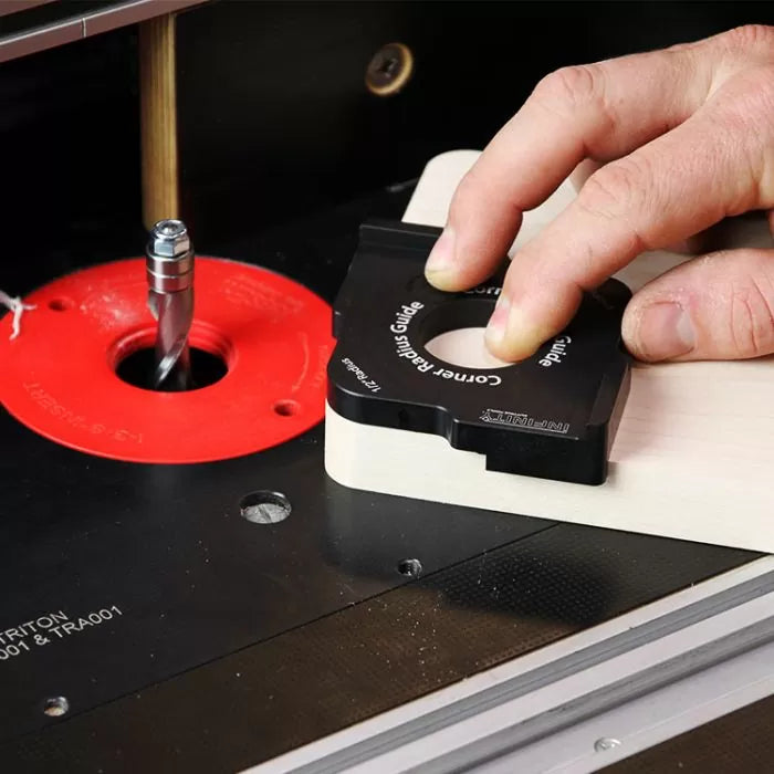 Woodworker using a corner radius guide on a router table with a router bit installed
