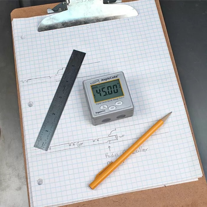 Digital angle gauge reading 45.00°, ruler, and pencil on graph paper with woodworking sketches