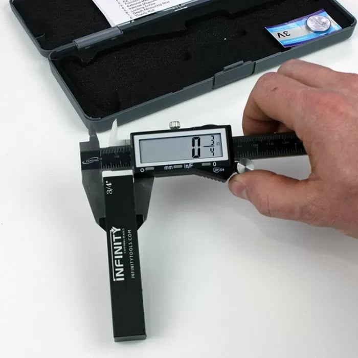 Digital caliper measuring woodworking router bit diameter on white surface