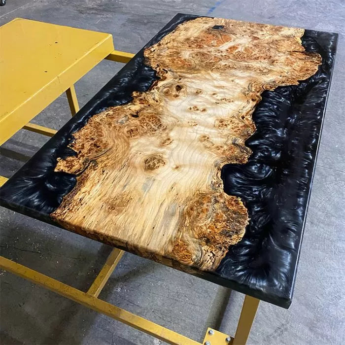 Live edge wood and black epoxy deep pour resin table on a yellow stand
