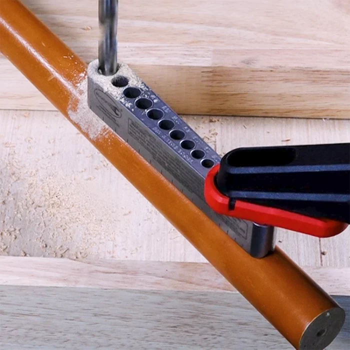 Dowel drilling jig clamped to wooden dowel for precise hole drilling in woodworking