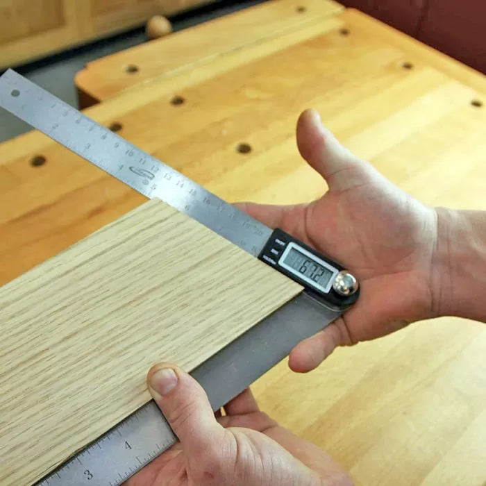 Digital angle finder measuring wood board on workbench, precision woodworking tool