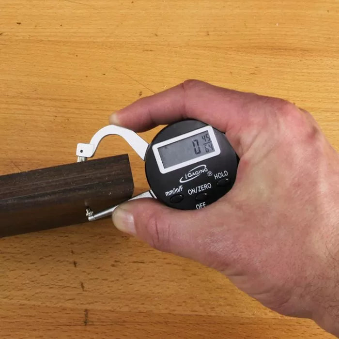 Measuring wood thickness with a digital caliper on a workbench