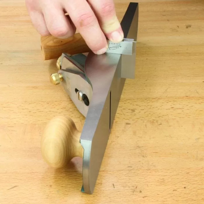 Woodworker checking flatness of hand plane sole with precision square on workbench