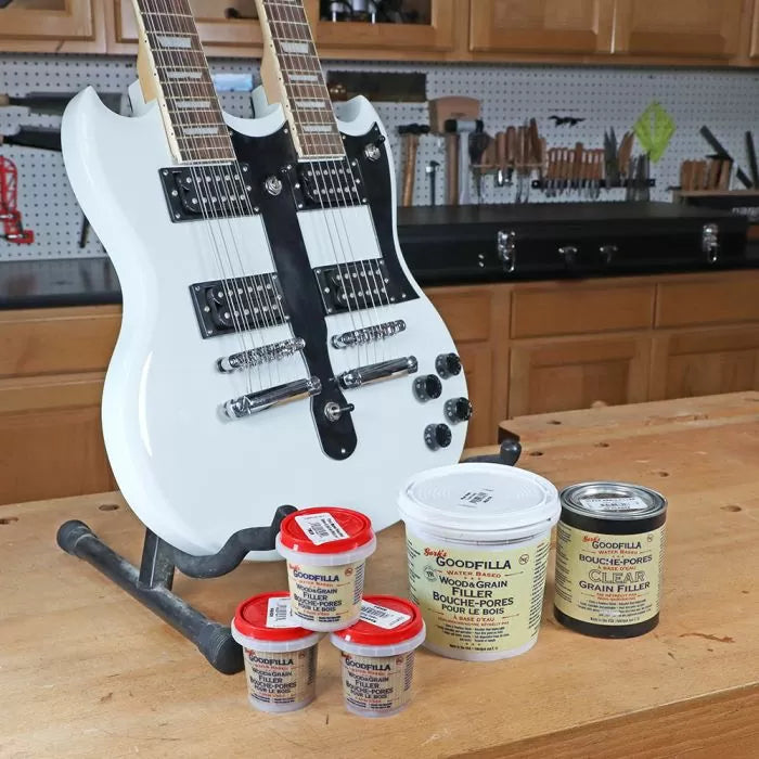 White double-neck electric guitar on workbench with wood grain fillers in woodworking shop