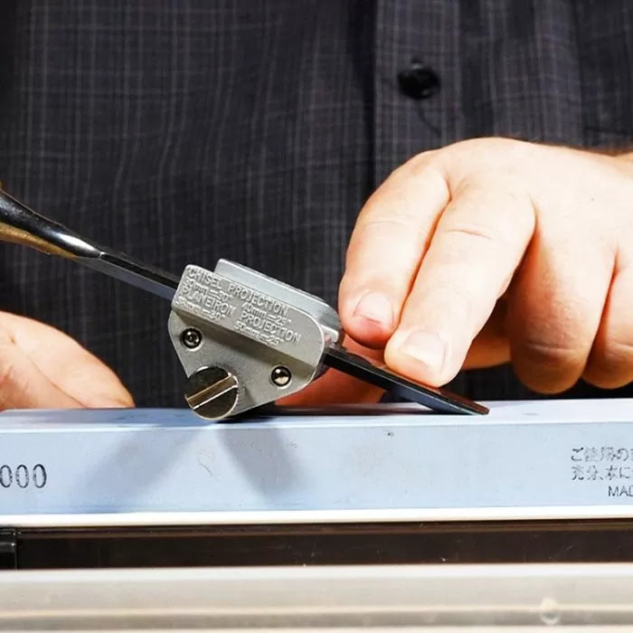 Sharpening a chisel with honing guide on sharpening stone, woodworking tool detail