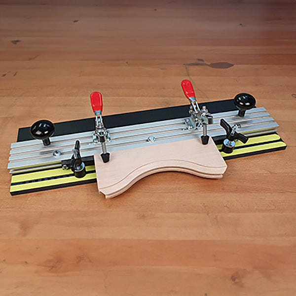 Woodworking jig with adjustable clamps holding curved wooden pieces on a workbench