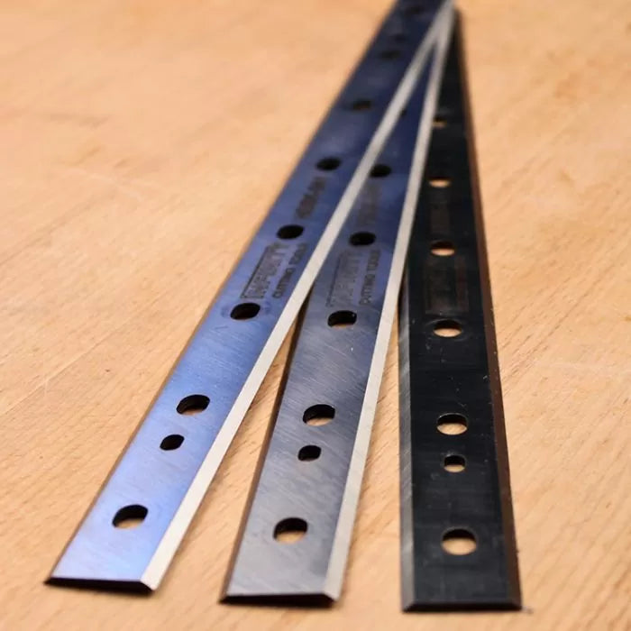 Set of three planer blades with mounting holes on a wood surface, woodworking tool accessory.