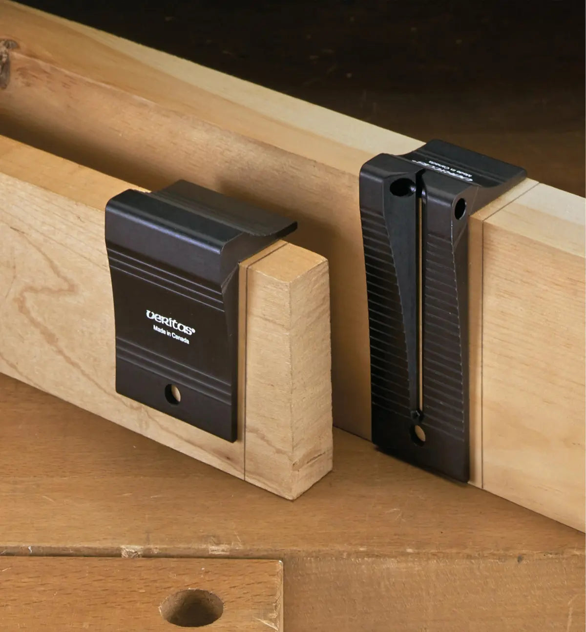 Two black woodworking planing stops attached to wooden boards on a workbench