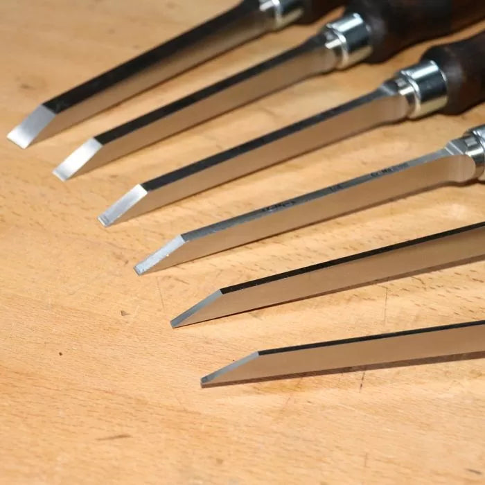 Set of sharp woodworking chisels with steel blades on a wooden workbench