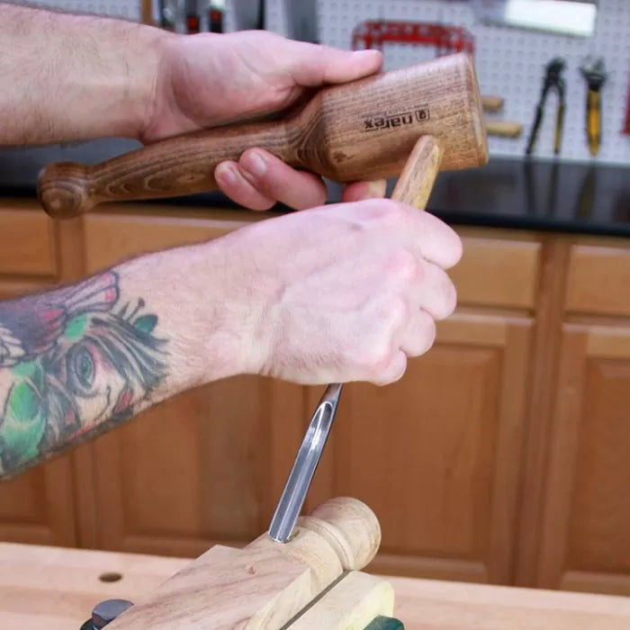 Woodworker using a wooden mallet and chisel for precise woodworking in a workshop