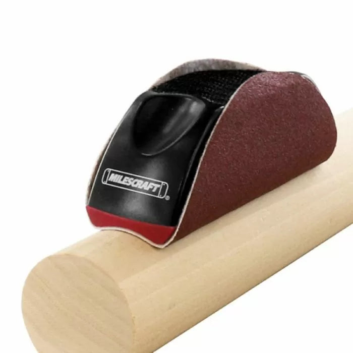 Concave sanding block smoothing a round wooden dowel, woodworking hand tool in use