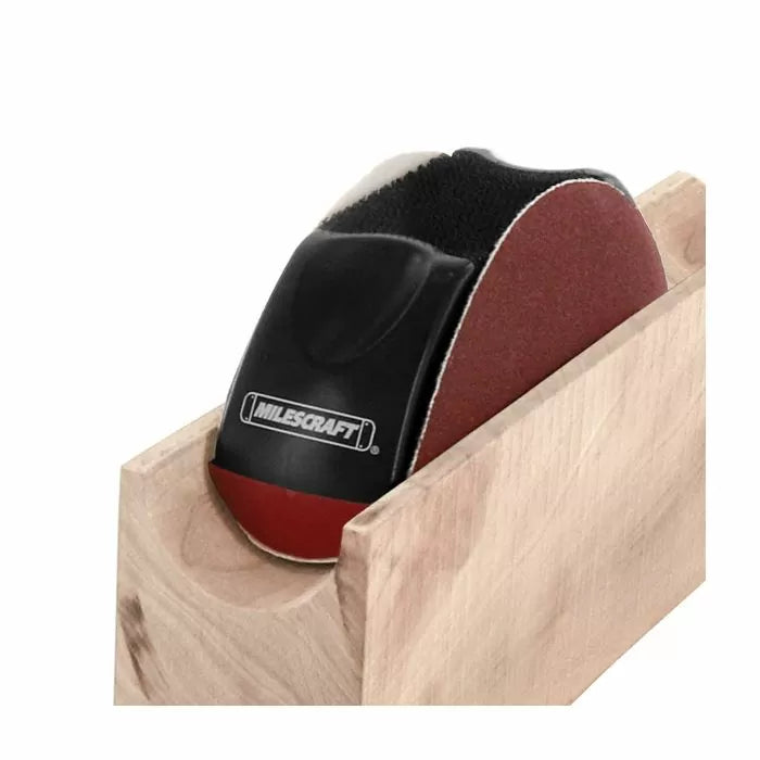 Hand sanding block smoothing a concave wood surface with sandpaper