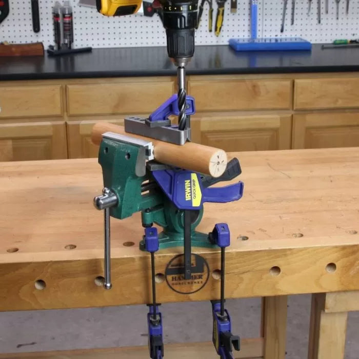 Wood dowel secured in vise, being drilled with power drill in woodworking shop