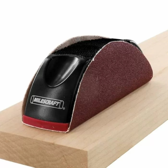 Hand sanding block smoothing wood surface, woodworking tool in use