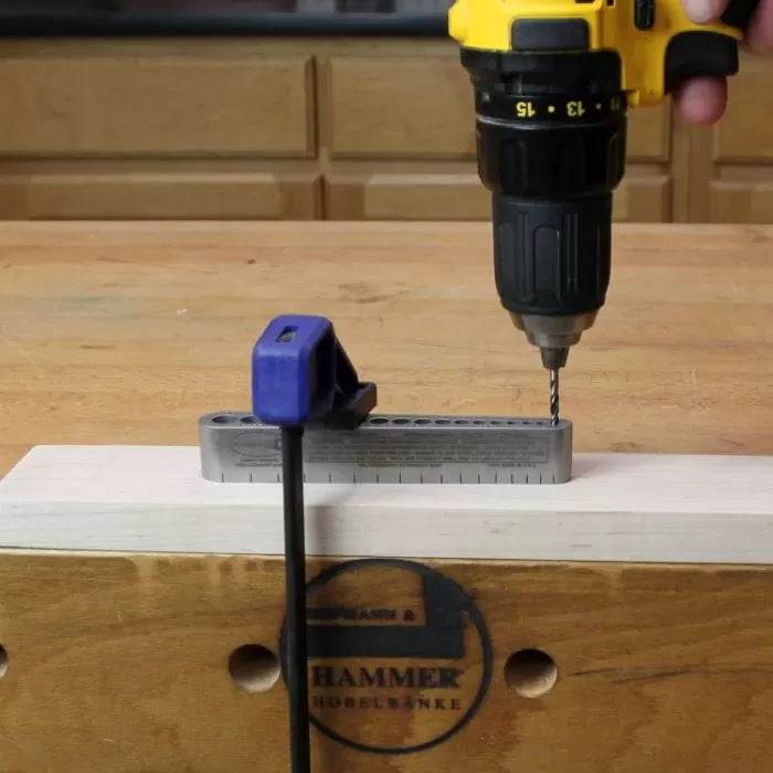 Cordless drill and dowel jig clamped to wood for precise woodworking hole drilling