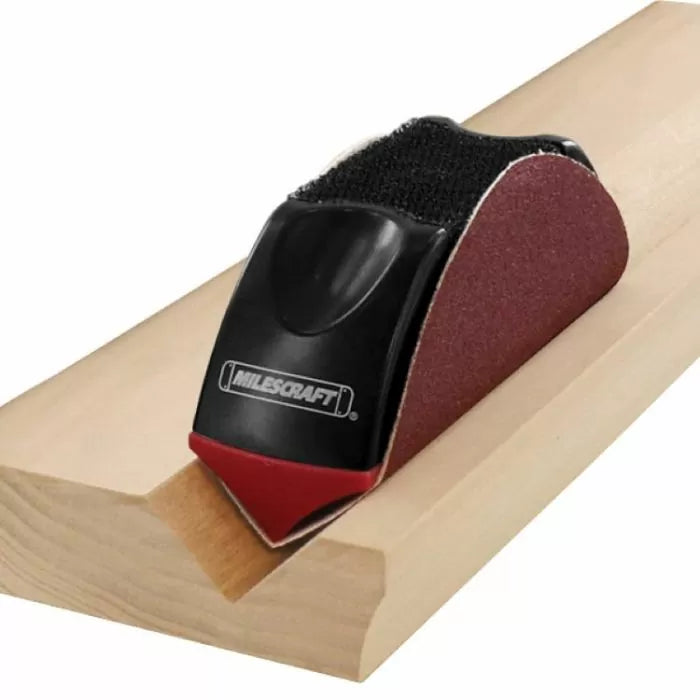 Handheld sanding block tool smoothing a wooden molding groove