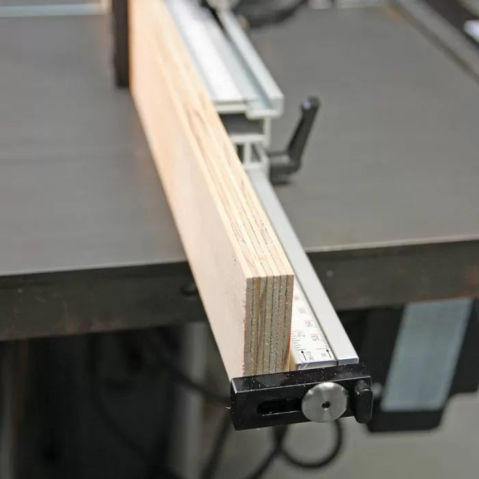 Plywood board aligned with a table saw fence and measuring guide for precise cutting
