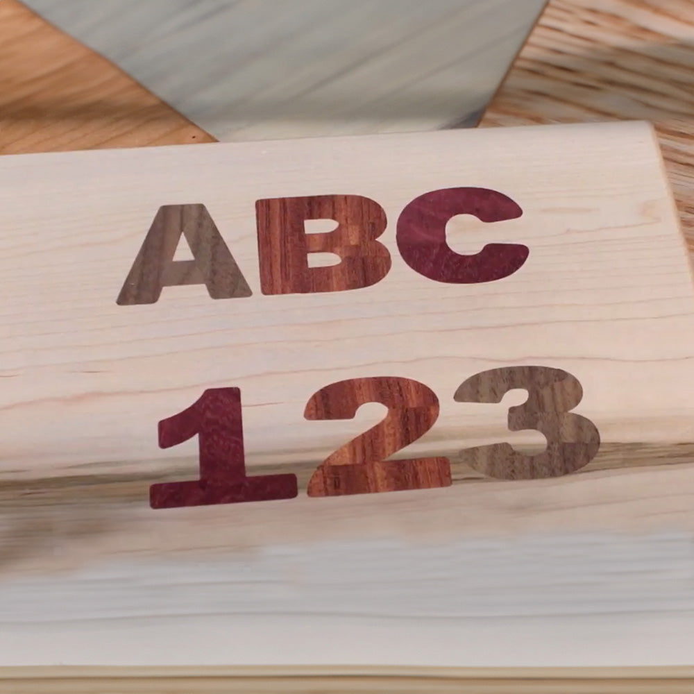 Wooden block with inlaid letters ABC and numbers 123, showcasing woodworking inlay technique