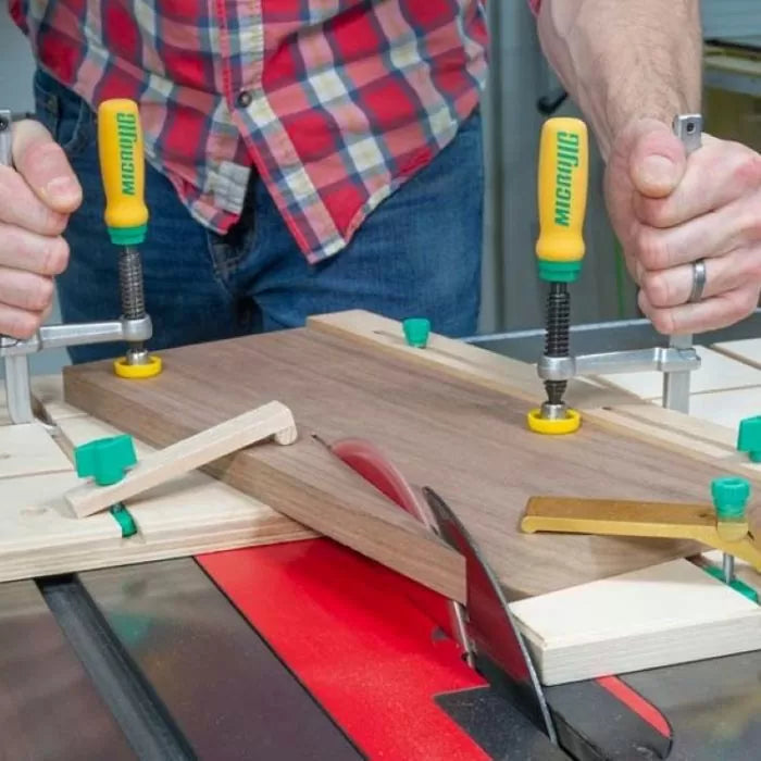 Woodworker using a matchfit jig system to secure wood on a table saw for precise cutting