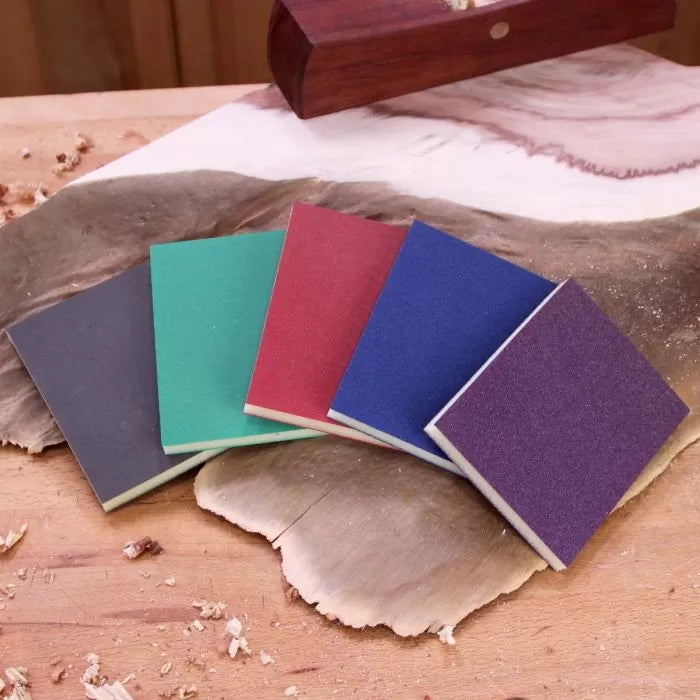 Assorted sanding sponge pads on woodwork surface for woodworking finishing tasks