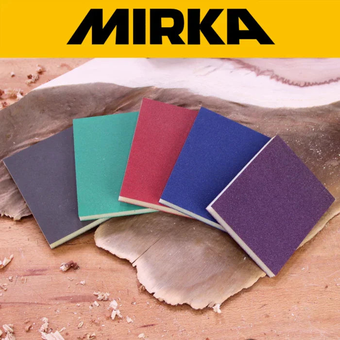 Colorful Mirka sanding sponges on a woodworking surface with wood shavings