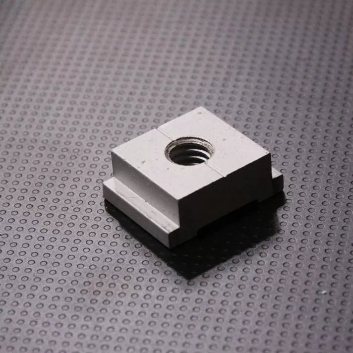 Aluminum miter track nut for woodworking jigs on a textured black surface