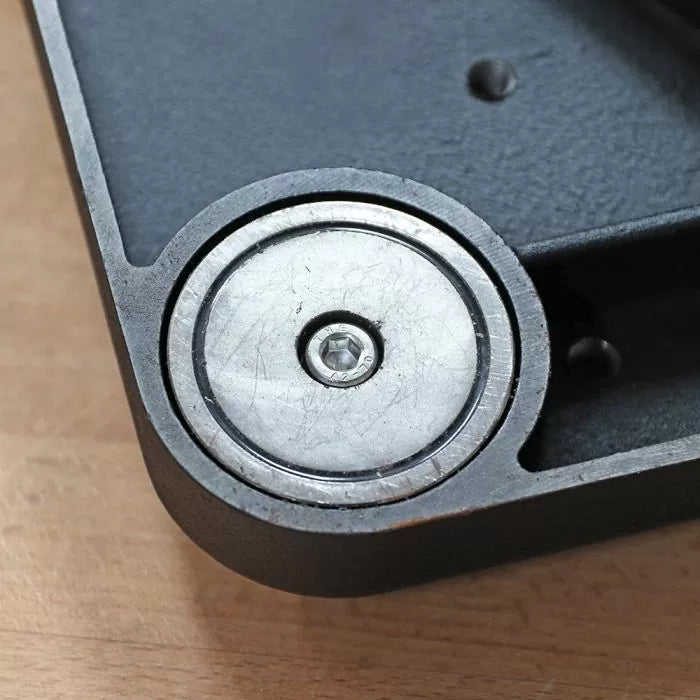 Close-up of a metal roller bearing mounted in a woodworking tool housing on wood surface
