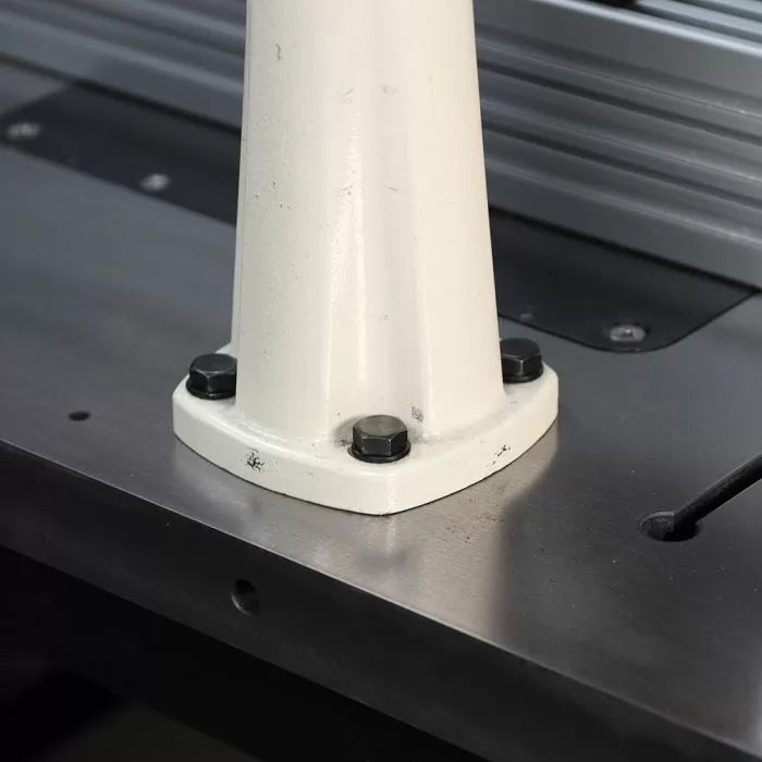 Close-up of a metal machine base secured with bolts on a woodworking table