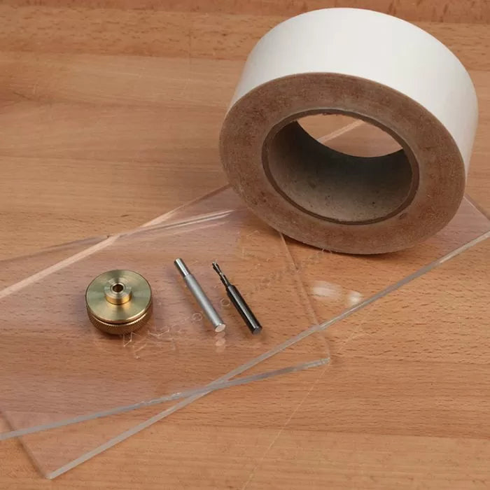 Woodworking template making kit with router bits, brass knob, acrylic sheets, and tape on workbench