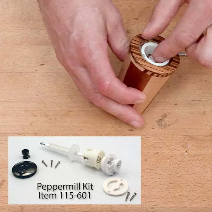 Hands assembling a wooden peppermill using components from a peppermill kit on a workbench.