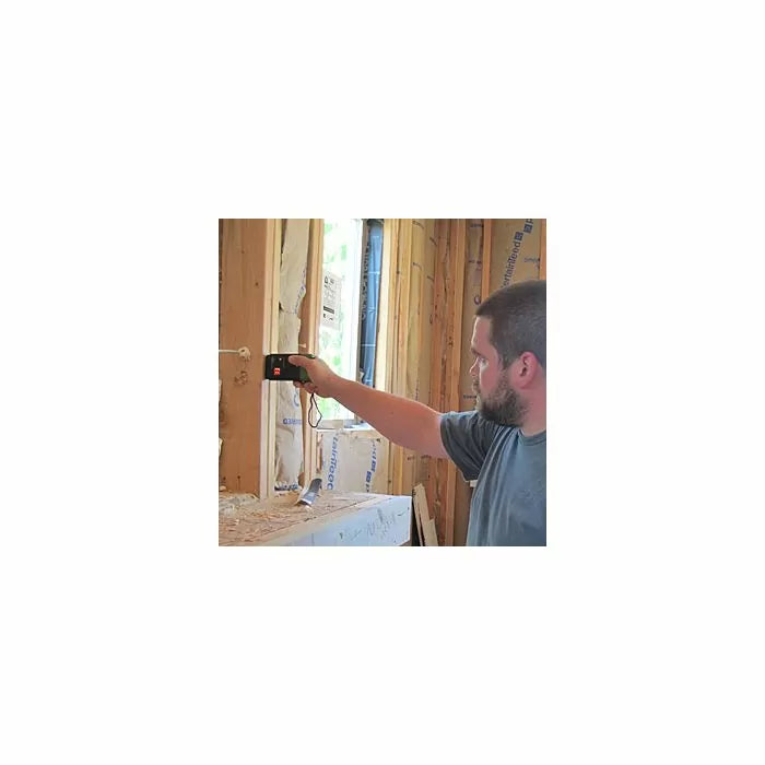 Man using a pin moisture meter to check wood framing in a house under construction