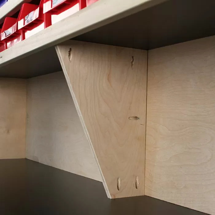 Wood shelf bracket with pocket hole joinery supporting a plywood workbench shelf