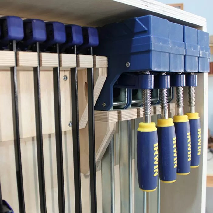 Woodworking bar clamps organized in a wooden rack, featuring blue Irwin handles