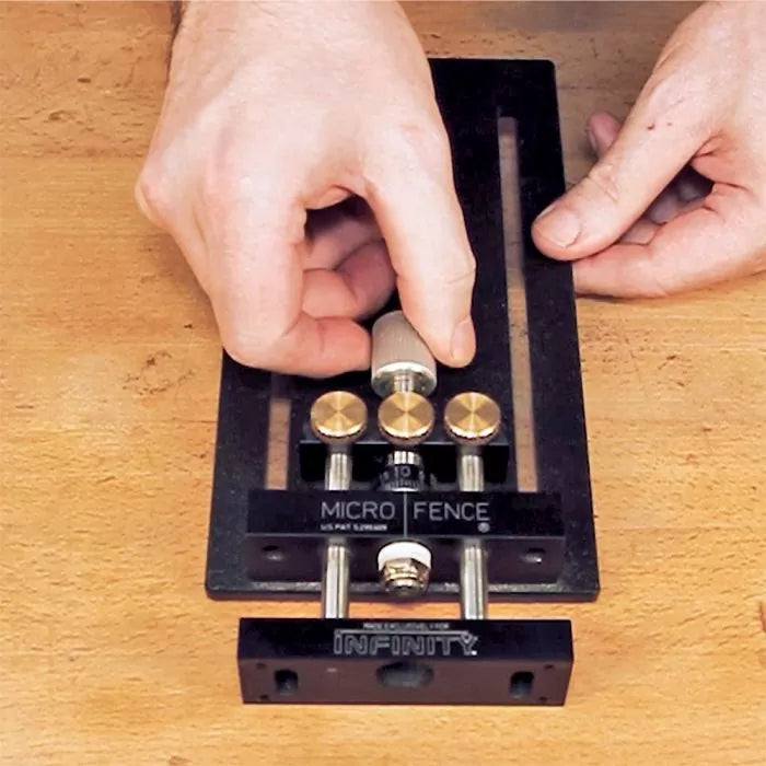 Hands adjusting a Micro Fence precision woodworking jig on a workbench