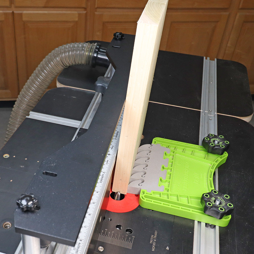 Router table with featherboard, vertical wood piece, and dust collection setup in workshop
