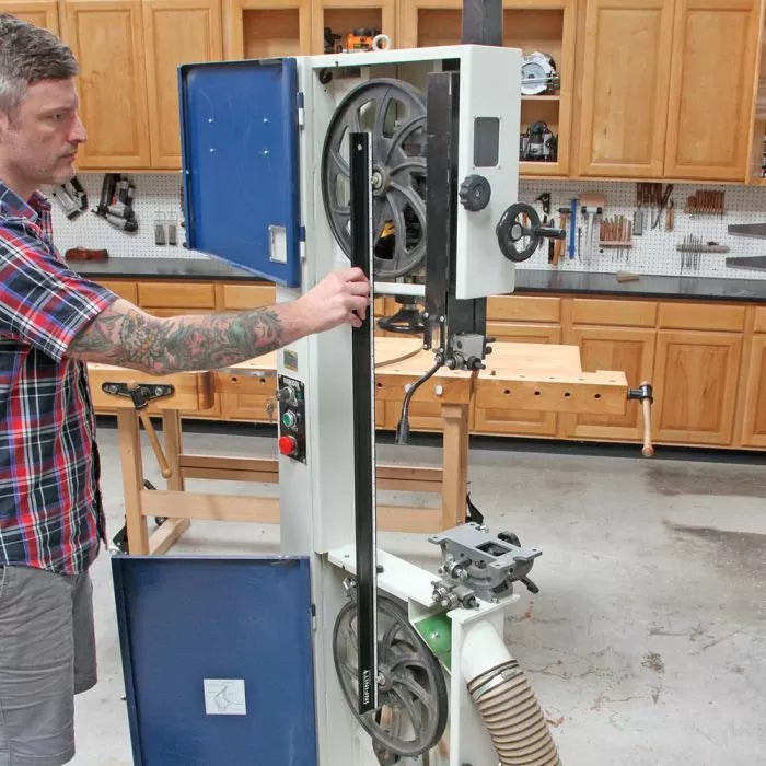 Man aligning bandsaw blade in woodworking shop, using precision tool for bandsaw adjustment