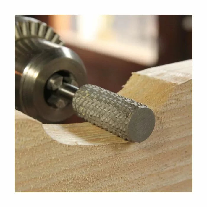 Close-up of rotary rasp shaping grooved edge on wood, woodworking tool in use