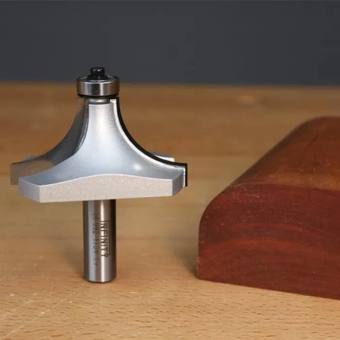 Roundover router bit next to routed wood edge on a woodworking table