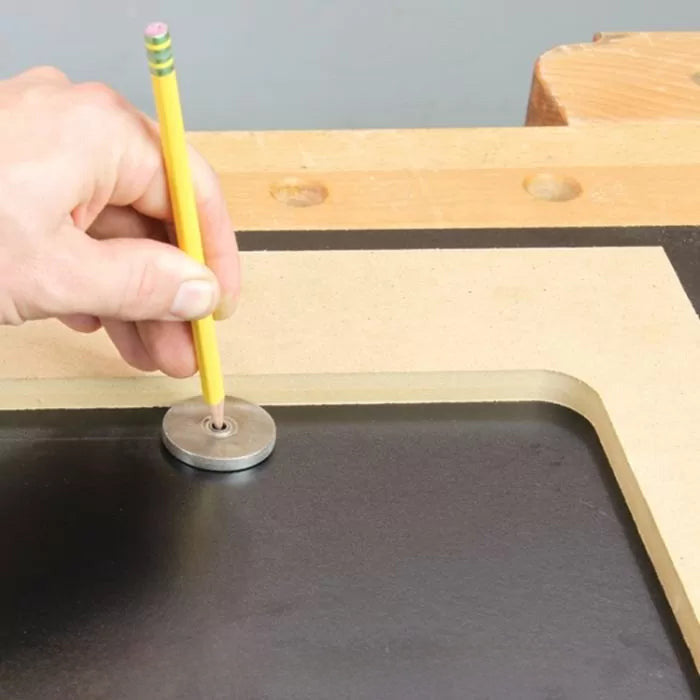 Hand tracing a wood template with a pencil and metal washer on a workbench