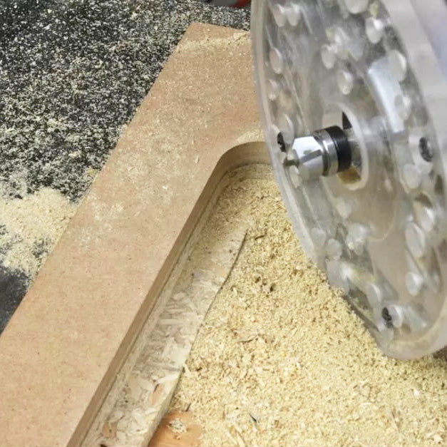 Close-up of a woodworking router cutting a groove in MDF with wood shavings visible
